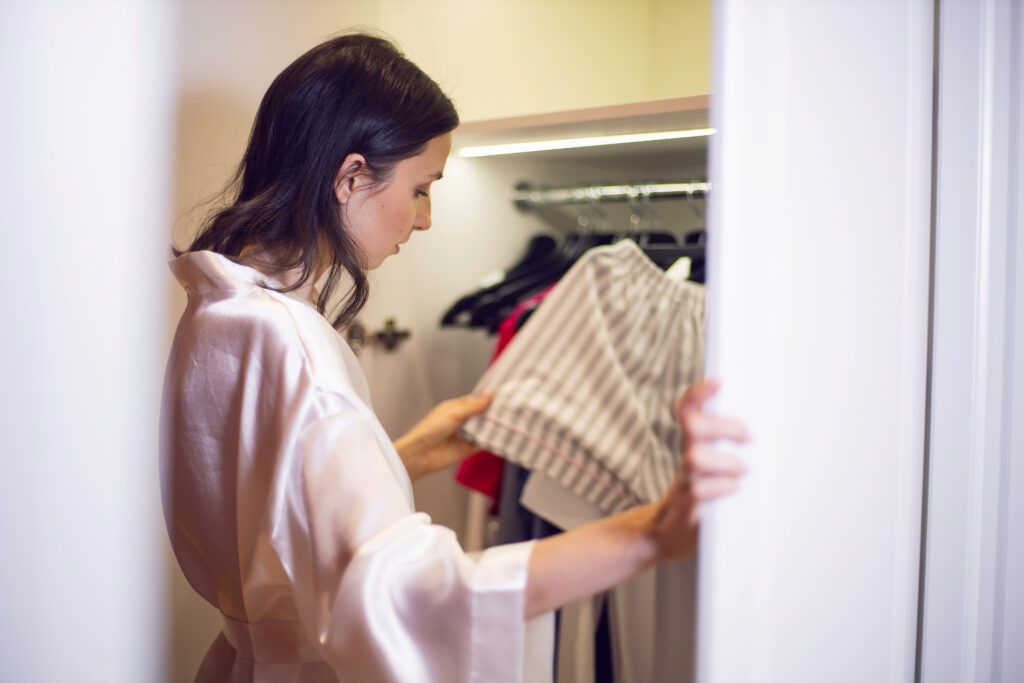 woman white bathrobe stands wardrobe with clothes chooses shirt