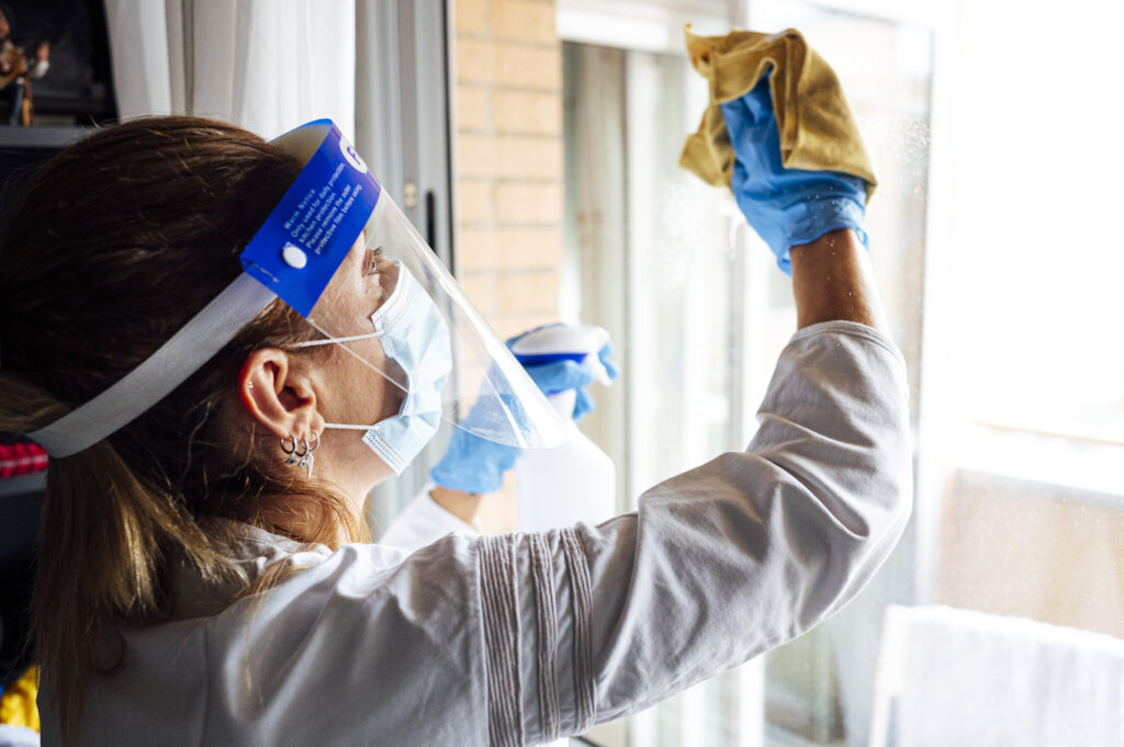 cleaning staff disinfecting house against virus wearing transparent protective mask